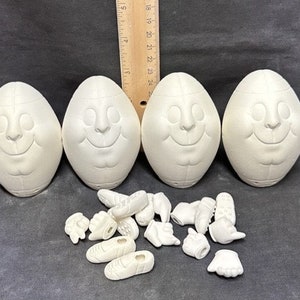 May include: Four white ceramic football-shaped ornaments with smiling faces, and a set of white ceramic hand and foot ornaments.