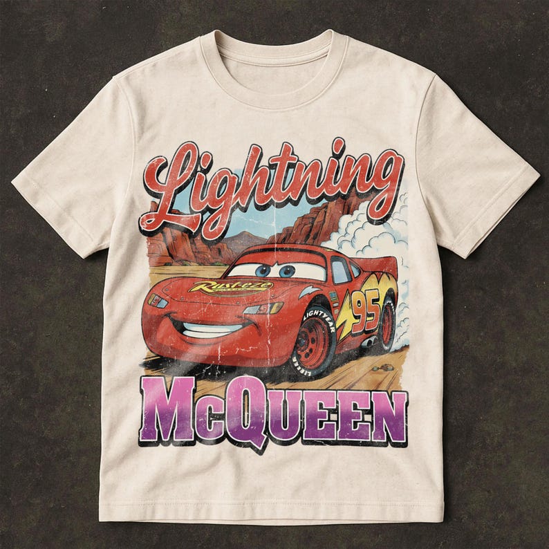 May include: Cream-colored t-shirt featuring a distressed graphic of Lightning McQueen, a red race car with the number 95. The text "Lightning McQueen" and "95" are prominently displayed in red and yellow, with the name "McQueen" in purple.