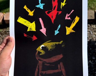 May include: A rectangular art print on a black background featuring a yellow fish with a white eye sitting on a brown stool. Above the fish are multiple hand-drawn arrows in various colors including red, yellow, pink, and light blue pointing downward.