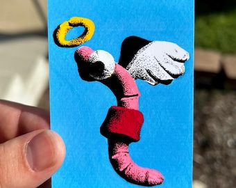May include: A rectangular sticker on a bright blue background featuring a pink worm character with white wings and a yellow halo. The worm is wearing a red band around its midsection, and the entire illustration has a stippled, textured appearance.