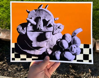 May include: A rectangular art print featuring a purple, textured, abstract sculpture of a creature and a cluster of grapes. The objects are set against a solid orange background and rest on a black and white checkered surface.