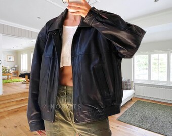 May include: A black leather bomber jacket with a collared neckline and a ribbed hem. The jacket has a classic design with a zipper closure and pockets. The leather appears to be smooth and has a slight sheen. The jacket is a versatile outerwear piece.
