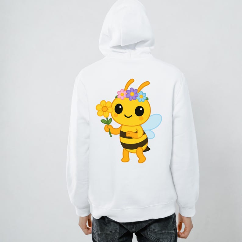 May include: White hoodie featuring a cartoon bee graphic on the back. The bee is yellow and black, holding a flower, and wearing a flower crown. The hoodie has a hood and a drawstring.