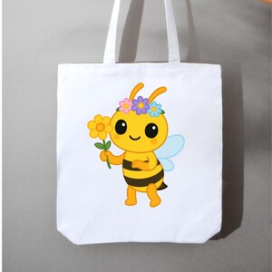 May include: White tote bag featuring a cartoon bee with a flower and a floral crown. The bee is yellow with black stripes, blue wings, and large black eyes. The tote bag has white handles and is made of a sturdy fabric.