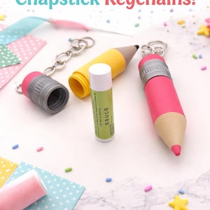May include: Adorable chapstick keychains in the shape of pencils. One is pink, one is yellow, and one is gray. A chapstick tube is in the center. The image has the text "Adorable Chapstick Keychains!"