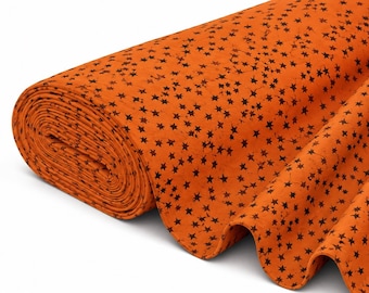 May include: A roll of bright orange fabric featuring a repeating pattern of small, dark brown, five-pointed stars. The textile has a textured, mottled appearance across the surface, with the fabric draped to show the thickness of the roll.