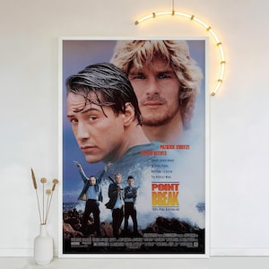 Peut inclure: Une affiche encadrée du film "Point Break" avec Keanu Reeves et Patrick Swayze. L'affiche a une palette de couleurs bleue et blanche avec le titre du film en grandes lettres en gras. L'affiche comprend également le texte "100% Pure Adrenaline."