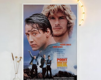 May include: A framed movie poster for "Point Break" featuring Keanu Reeves and Patrick Swayze. The poster has a blue and white color scheme with the movie title in large, bold letters. The poster also includes the text "100% Pure Adrenaline."