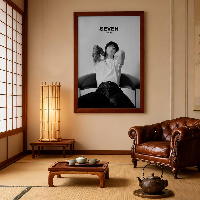May include: A framed black and white poster with the word "SEVEN" at the top. The poster features a person in a white t-shirt and black pants. The room includes a bamboo lamp, a brown leather armchair, and a low wooden table.