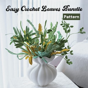 Op de afbeelding: Een witte keramische vaas met een gerimpelde rand bevat een boeket van gehaakte bladeren in tinten groen en geel. De bladeren zijn in een natuurlijke, vloeiende stijl gerangschikt. De tekst "Easy Crochet Leaves Bundle Pattern" wordt boven de vaas weergegeven.
