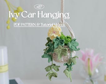 Op de afbeelding: Een gehäkelde hangende plantenpot met een gele bloem en groene klimopbladeren. De pot is gemaakt van wit garen en heeft een bruin touw waaraan hij hangt. De tekst "Ivy Car Hanging" en "PDF Pattern & Tutorial Videos" is zichtbaar in de afbeelding.