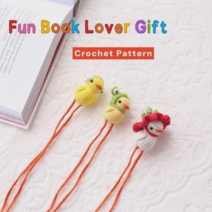 以下が含まれることがあります： オレンジ色の紐が付いた、鳥の形をした手作りのかぎ針編みのブックマークが3つ。1つは黄色、1つは緑の帽子をかぶった黄色、3つ目は赤い頭飾りをつけた白です。「Fun Book Lover Gift」と「Crochet Pattern」の文字が見えます。