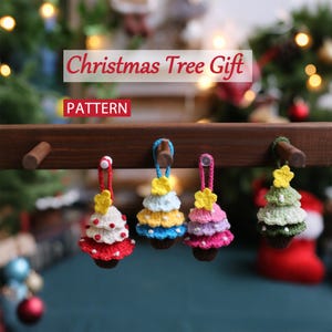 Puede incluir: Adornos de árbol de Navidad tejidos a ganchillo en rojo, blanco, amarillo, azul, rosa y verde. Cada árbol tiene un lazo para colgar y una estrella amarilla. El texto "Christmas Tree Gift" y "PATTERN" es visible.