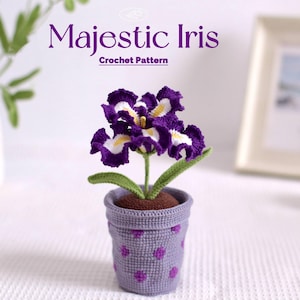 May include: A crocheted iris flower in a small purple pot with a polka dot pattern. The flower has purple petals with white and yellow accents. The text "Majestic Iris Crochet Pattern" is at the top.