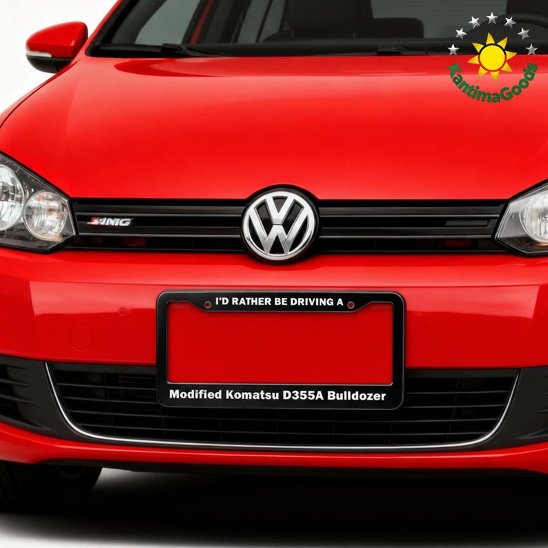 Puede incluir: Un coche Volkswagen rojo con una parrilla negra y un marco de matr&iacute;cula. El marco de la matr&iacute;cula dice "I'D RATHER BE DRIVING A" encima de una matr&iacute;cula roja. Debajo de la placa, dice "Modified Komatsu D355A Bulldozer."