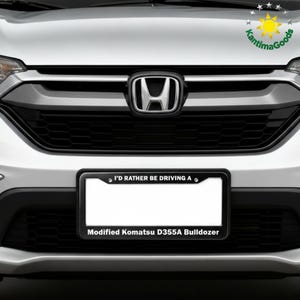 Puede incluir: Primer plano de la parte delantera de un coche, con un marco de matr&iacute;cula negro con el texto "I'D RATHER BE DRIVING A" y "Modified Komatsu D355A Bulldozer". El coche tiene una parrilla negra y un emblema de Honda.