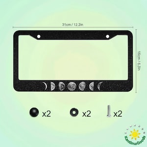 May include: Black license plate frame with a glittery texture, featuring the phases of the moon. The frame measures 31cm wide and 16cm high. Includes mounting hardware: screws, caps, and washers.