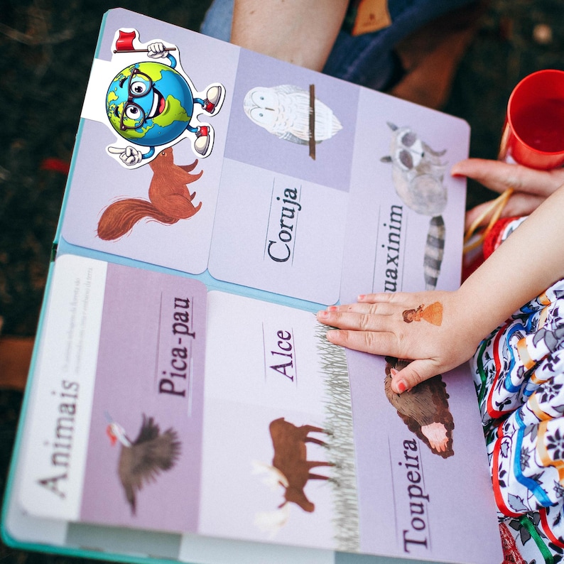 Pu&ograve; includere: Un libro educativo per bambini intitolato Animais con illustrazioni di uno scoiattolo, un gufo, un procione, un picchio, un alce e una talpa. Un personaggio a forma di globo terrestre con occhiali e una bandierina rossa &egrave; fissato in alto.