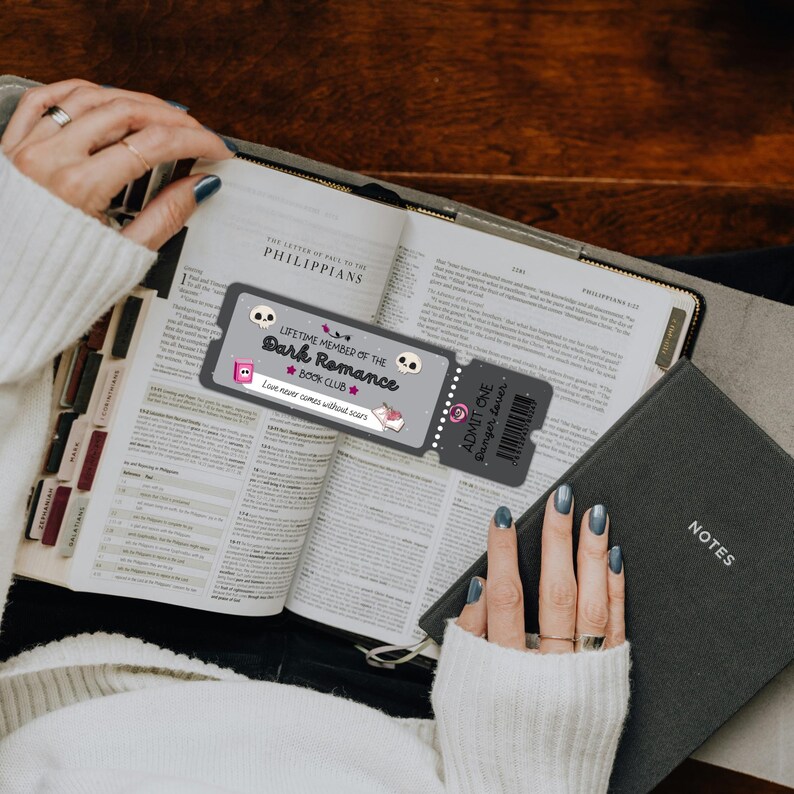 May include: An open book with a bookmark that reads "LIFETIME MEMBER OF THE Dark Romance BOOK CLUB". A small notebook labeled "NOTES" is next to the book. The bookmark has a skull and a ticket that says "ADMIT ONE Danger Lover".