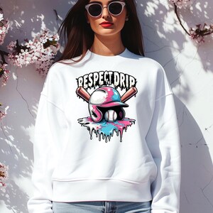 May include: White sweatshirt with a graphic of a baseball helmet with pink and blue paint dripping down. The text "Respect the Drip" is above the helmet.
