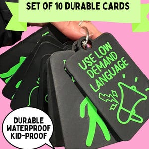 May include: A set of 10 black rectangular communication cards on a metal ring. Each card features raised bright green text and icons. The top card displays the text USE LOW DEMAND LANGUAGE with a megaphone icon. The cards are durable and waterproof.