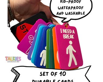 May include: A set of 10 rectangular communication cards on a ring, featuring various colors including pink, orange, green, blue, and black. Each card displays white graphic icons and text such as I NEED A BREAK and STOP. The text DURABLE KID-PROOF WATERPROOF AND WASHABLE is visible in a speech bubble, and SET OF 10 DURABLE CARDS is printed below.