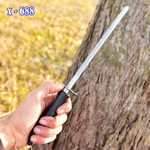 May include: A knife sharpening steel with a black handle and a silver sharpening rod. The text "X-688" is visible in the upper left corner. The tool is held in front of a tree trunk.