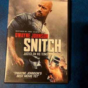 May include: DVD case for the movie "Snitch" starring Dwayne Johnson. The cover features Johnson in a denim shirt, with the title in large white letters. Text includes "Inspired by True Events" and "Justice on His Terms."