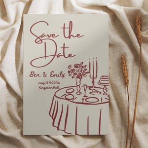 May include: A wedding invitation card with the text "Save the Date" in burgundy script. The card includes the names "Ben & Emily", date, time, and location. A burgundy illustration of a table setting with flowers and candles is also featured.