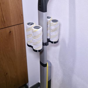 May include: A gray and yellow floor cleaner with four white and yellow roller brushes attached. The cleaner has a long handle and a yellow base. The brushes are cylindrical and appear to be made of a soft, absorbent material.