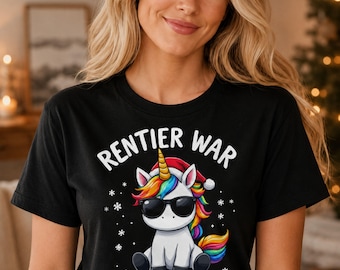 Könnte beinhalten: Ein schwarzes T-Shirt mit kurzen Ärmeln und einem Aufdruck eines weißen Einhorns mit roter Weihnachtsmütze und schwarzer Sonnenbrille. Das Einhorn hat eine regenbogenfarbene Mähne und einen Schweif. Der Text RENTIER WAR AUSVERKAUFT steht in Weiß.