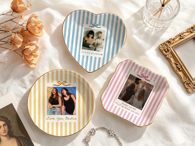 Peut inclure: Trois coupelles en c&eacute;ramique &agrave; bordure dor&eacute;e, orn&eacute;es de rayures verticales bleues, jaunes et roses. Chaque coupelle pr&eacute;sente une photographie personnalis&eacute;e et du texte, notamment "Love live friendship", "Love You Bestie" et "Sister est. 1998 Maid of honor est. 2021."