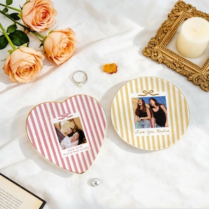 Peut inclure: Un plat en c&eacute;ramique en forme de c&oelig;ur &agrave; rayures roses et un plat rond &agrave; rayures dor&eacute;es, tous deux orn&eacute;s de photos personnalis&eacute;es. Le plat en c&oelig;ur affiche une photo avec le texte "Sister est 1994 Maid of honor est 2024" et le plat rond "Love You Bestie".