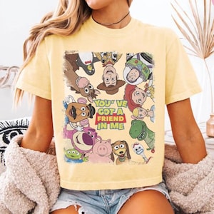 May include: Yellow t-shirt featuring a colorful graphic of characters from the animated film Toy Story. The text "You've Got a Friend in Me" is displayed in a red and yellow box. The shirt is short-sleeved.