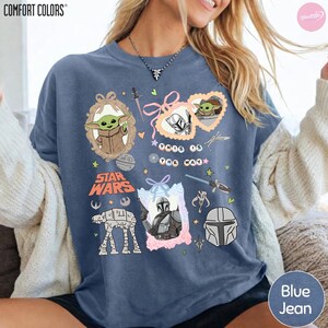 May include: Blue jean-colored sweatshirt featuring Star Wars characters and phrases. The design includes images of Grogu, the Mandalorian, and the text "This is the Way." The sweatshirt has a crew neck and long sleeves.