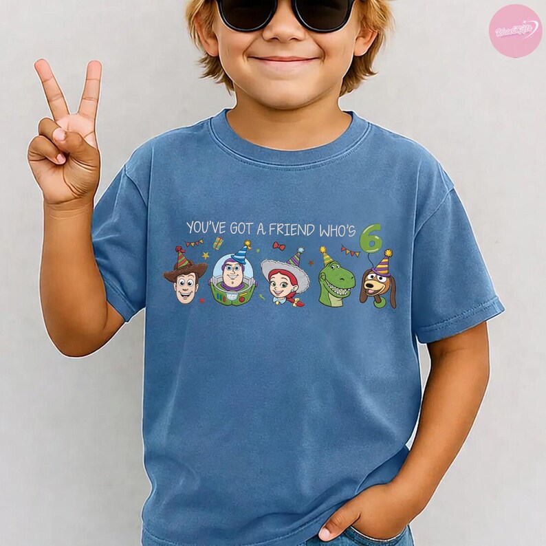 K&ouml;nnte beinhalten: Blaues T-Shirt mit dem Aufdruck "YOU'VE GOT A FRIEND WHO'S 6" und Toy Story-Figuren. Das Design zeigt Woody, Buzz Lightyear, Jessie, Rex und Slinky Dog, alle mit Partyh&uuml;ten.