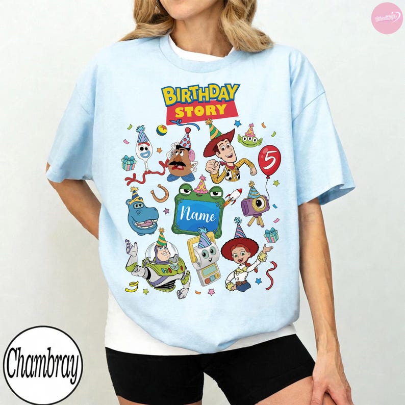 May include: A light blue t-shirt featuring a colorful graphic with the text "BIRTHDAY STORY" and "Name" in the center. The design includes various animated characters wearing party hats, a red balloon with the number 5, and confetti elements.