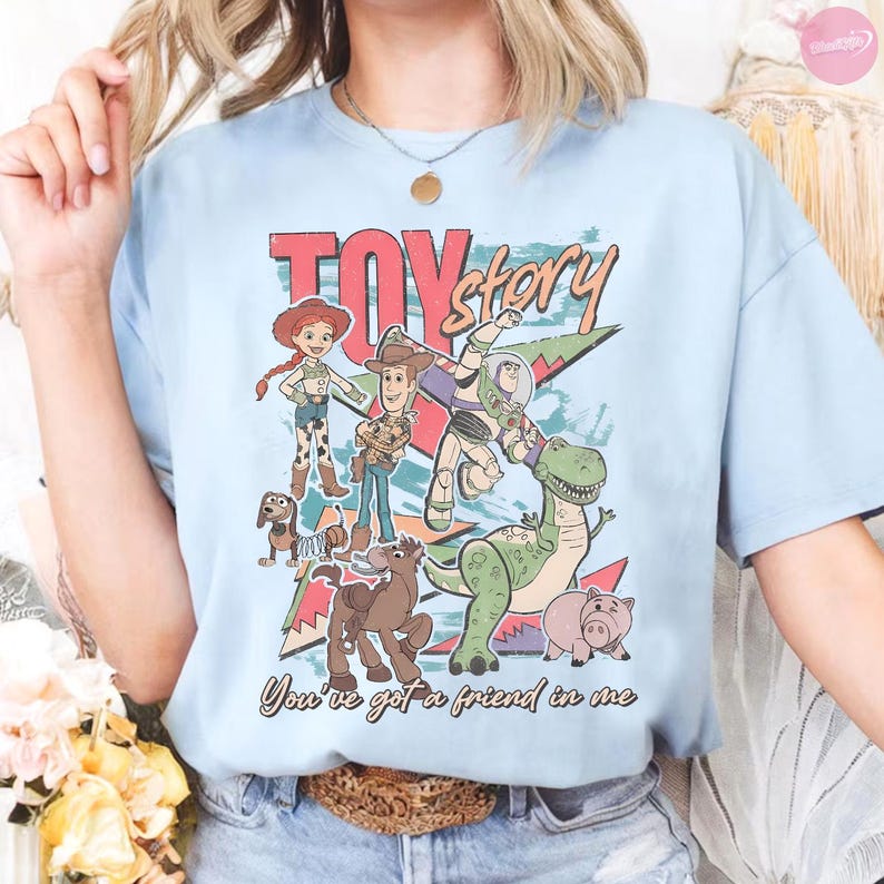 Puede incluir: Camiseta azul claro con un dise&ntilde;o gr&aacute;fico de personajes de la pel&iacute;cula "Toy Story". El dise&ntilde;o incluye el texto "Toy Story" en rojo y la frase "You've got a friend in me". La camiseta tiene cuello redondo y mangas cortas.