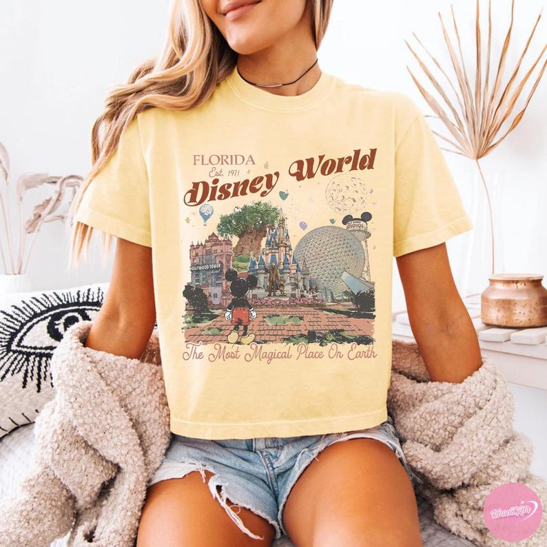 May include: Yellow t-shirt featuring a vintage-style illustration of Disney World in Florida. The graphic includes Mickey Mouse, the castle, and the text "Florida Disney World" and "The Most Magical Place On Earth."