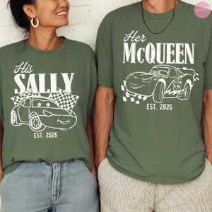 May include: Two olive green t-shirts with white graphics. One shirt says "His SALLY" with a car illustration and "EST. 2026". The other says "Her McQUEEN" with a car illustration and "EST. 2026".