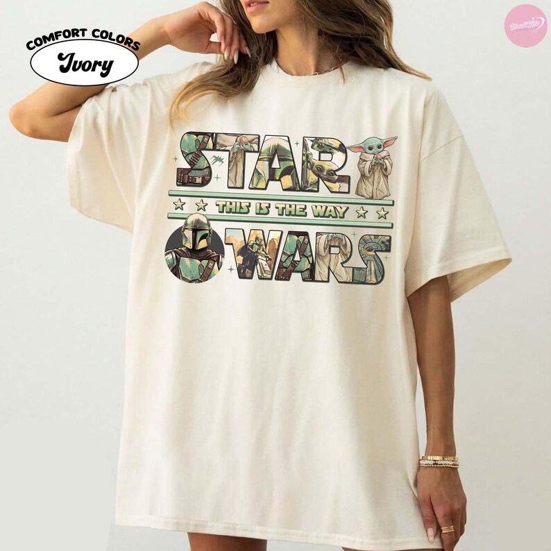 Puede incluir: Camiseta Comfort Colors color marfil con la frase "STAR WARS" en un dise&ntilde;o colorido. La camiseta incluye im&aacute;genes de personajes y la frase "THIS IS THE WAY". Una camiseta gr&aacute;fica con tem&aacute;tica de Star Wars.