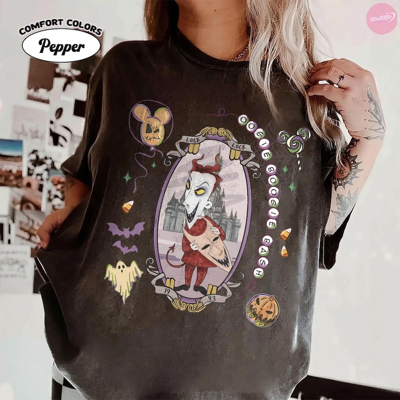 May include: A charcoal gray t-shirt featuring a graphic of the character Lock from The Nightmare Before Christmas inside an oval frame. The design includes the text OOGIE BOOGIE BASH, a ghost, bats, candy corn, a pumpkin, and a balloon.