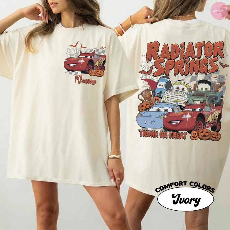 May include: An ivory t-shirt featuring a small red race car graphic on the front chest with the text Name. The back displays a large graphic of multiple cartoon cars in Halloween costumes with the text Radiator Springs Trunk or Treat.