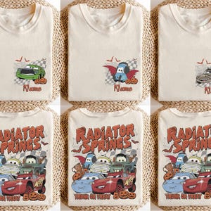May include: A collection of cream-coloured t-shirts featuring Halloween-themed graphics of cartoon cars. Some designs show individual cars with pumpkins and bats, while others display a group of cars with the text Radiator Springs Trunk or Treat.
