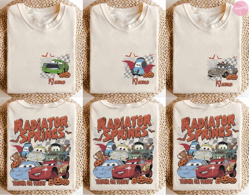 May include: A collection of cream-coloured t-shirts featuring Halloween-themed graphics of cartoon cars. Some designs show individual cars with pumpkins and bats, while others display a group of cars with the text Radiator Springs Trunk or Treat.