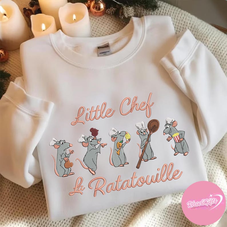 Pode incluir: Camisola branca com bordado coral "Little Chef La Ratatouille". Apresenta cinco ratos chefes de desenho animado com chap&eacute;us brancos, cada um segurando um utens&iacute;lio de cozinha. Um design divertido e acolhedor.