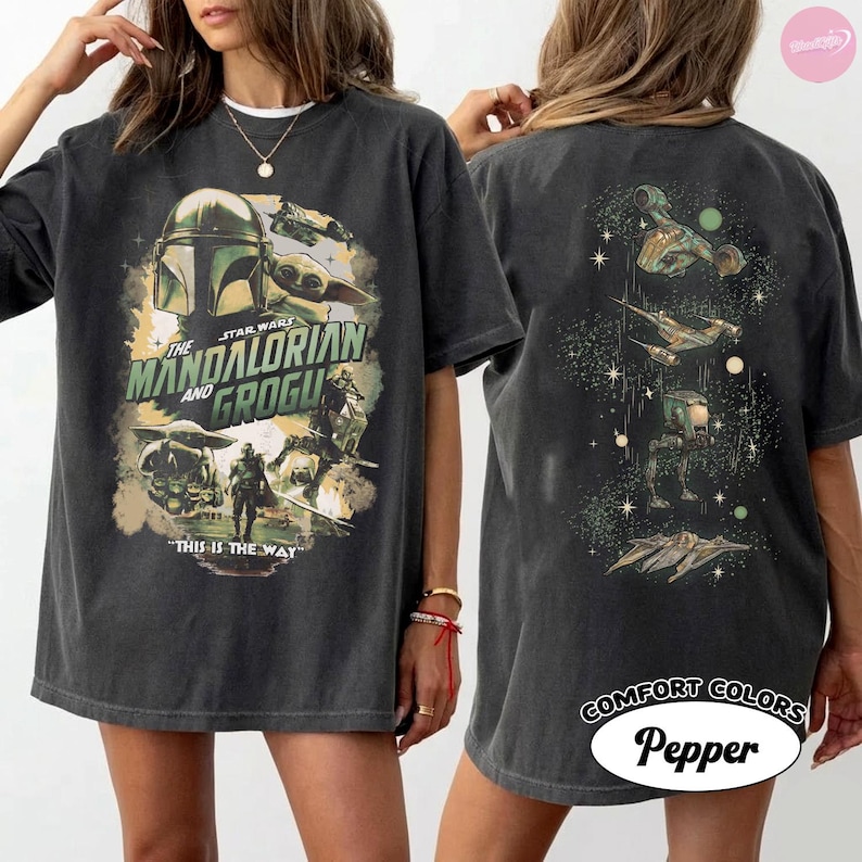 Puede incluir: Camiseta gris oscuro con un gr&aacute;fico de "The Mandalorian" con el texto "The Mandalorian and Grogu" y "This is the Way". La parte trasera de la camiseta tiene un dise&ntilde;o a juego. La camiseta est&aacute; etiquetada como "Comfort Colors Pepper."