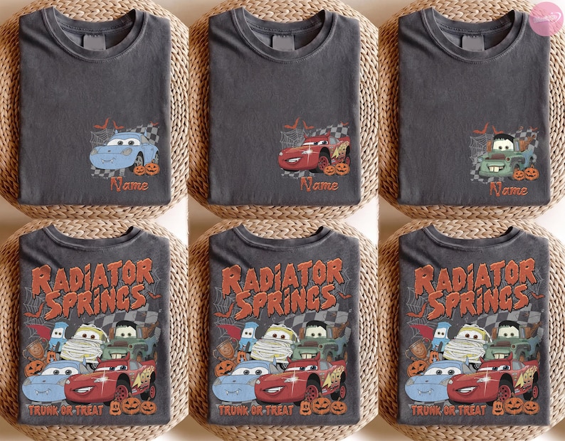May include: A collection of charcoal grey t-shirts featuring Disney Cars characters in Halloween themes. Some shirts show individual cars with the text Name, while others display the full group with Radiator Springs Trunk or Treat text.
