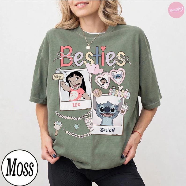Puede incluir: Camiseta verde oliva con la palabra "Besties" en colores pastel. La camiseta presenta im&aacute;genes estilo polaroid de Lilo y Stitch, junto con gr&aacute;ficos de corazones, helados y palomitas de ma&iacute;z. La camiseta es de corte holgado.