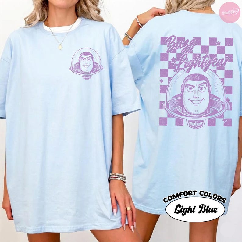 以下が含まれることがあります： バズ・ライトイヤーのグラフィックが特徴のライトブルーのTシャツ。シャツの前面には小さなバズ・ライトイヤーの画像があり、背面には「Buzz Lightyear」の文字と市松模様の大きなデザインが施されています。シャツには「Comfort Colors Light Blue」と表示されています。